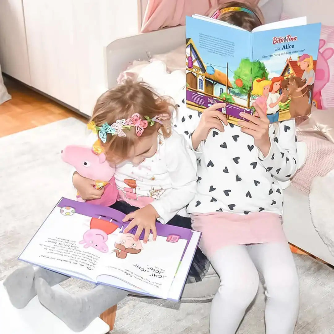 Zwei Mädchen lesen personalisierte Kinderbücher von Bibi und Tina und Peppa Pig