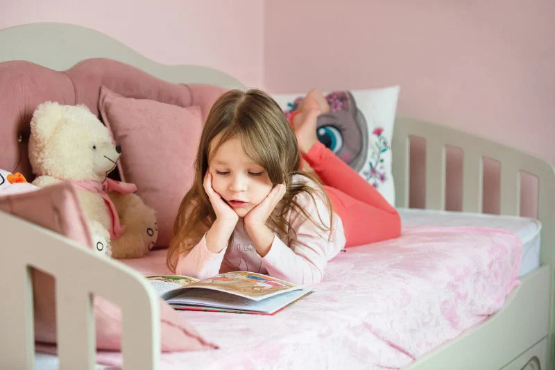 Mädchen liest im Bett liegend ein Buch