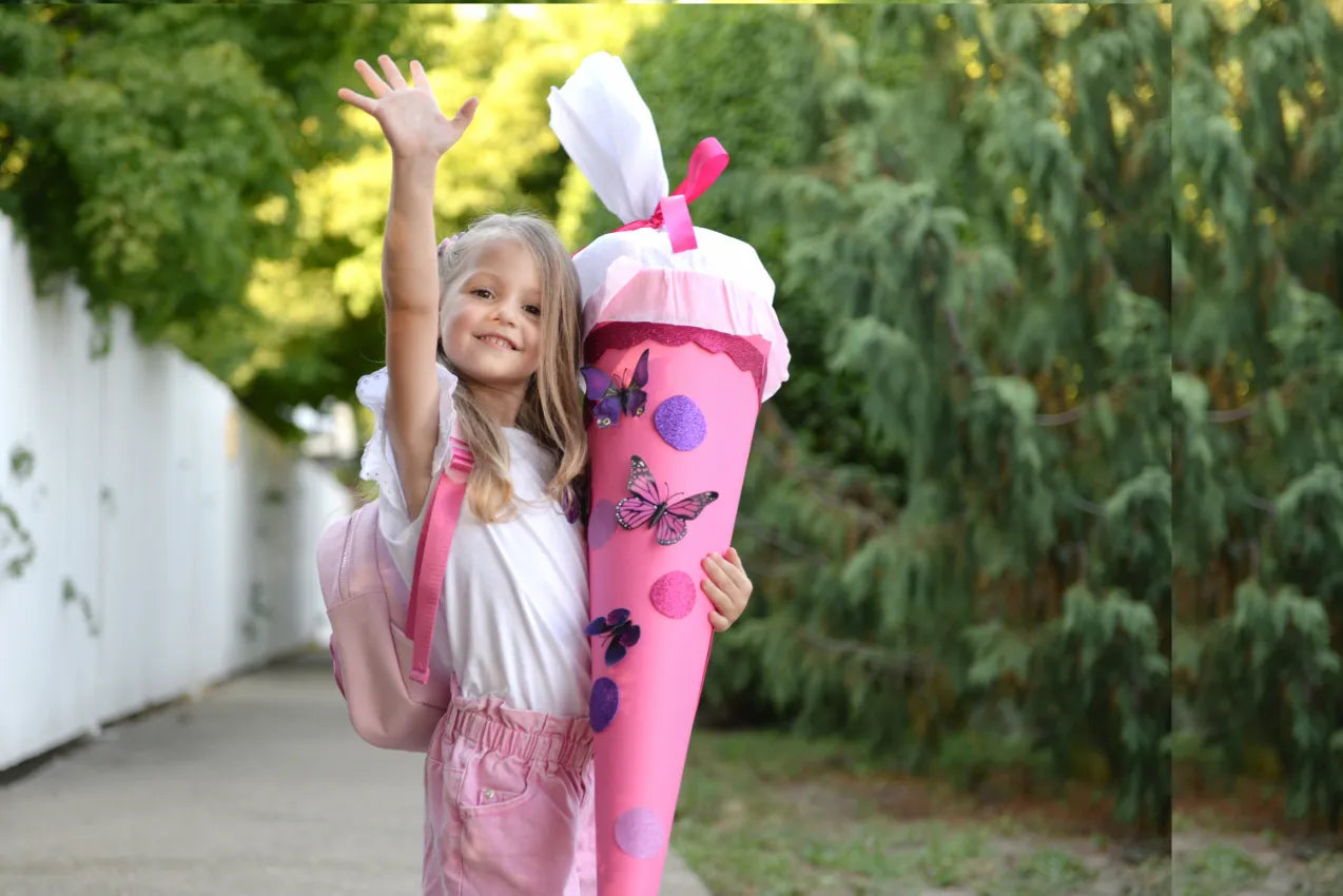 Mädchen mit Schultüte in der Hand winkt
