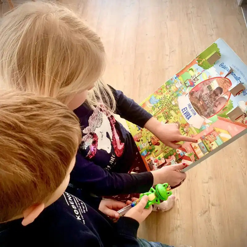 Zwei kleine Kinder sitzen auf dem Boden und erforschen gemeinsam den Framily Oster-Countdown-Kalender.