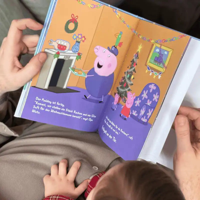 Vater liest einem Kind das Buch Peppa Pig Weihnachten vor