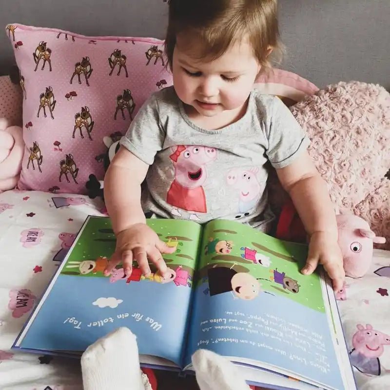 Ein kleines Mädchen liest ein Peppa Wutz Buch