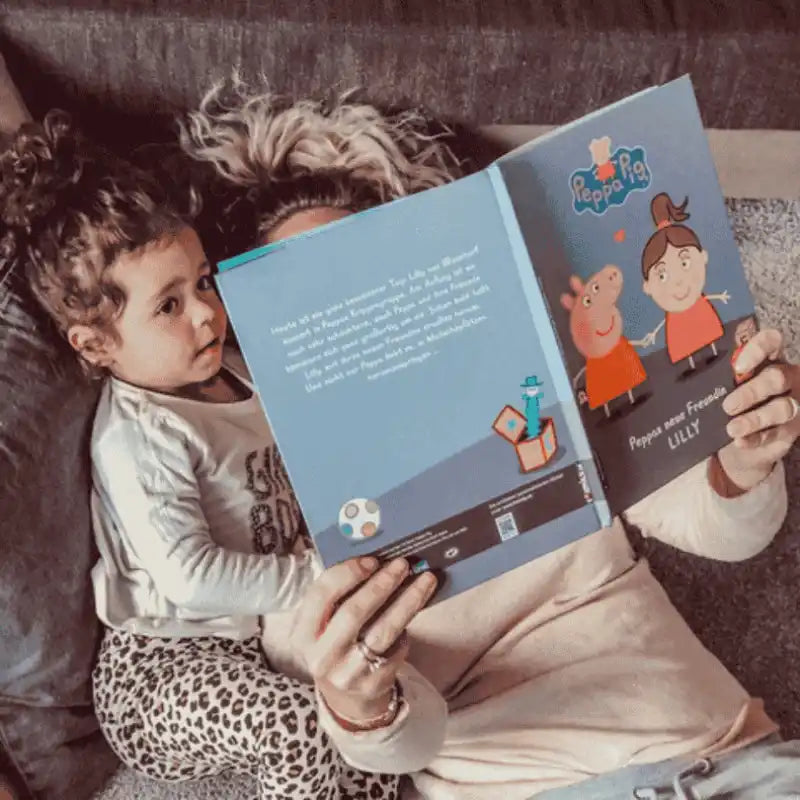 Kind und Mutter sehen sich ein personalisiertes Kinderbuch von Peppa Wutz an