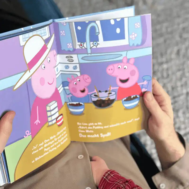 Person hält aufgeschlagenes Peppa Wutz Buch in der Hand